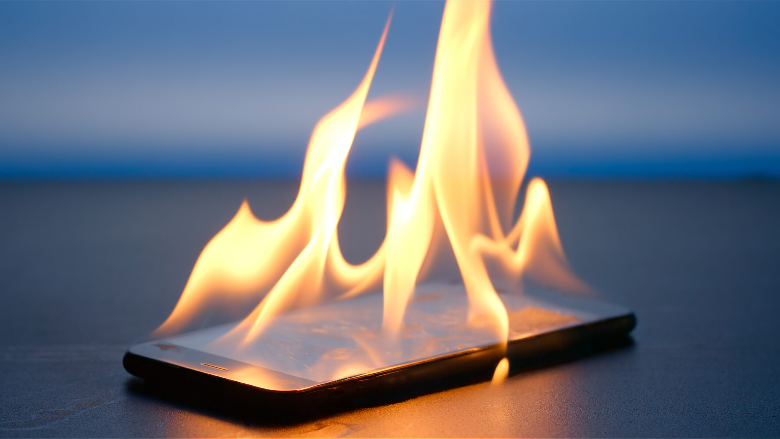 Smartphone is burning on a table on a blue background